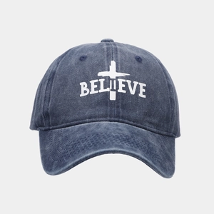Close-up of BELIEVE embroidery and cross pattern on washed navy denim baseball cap
