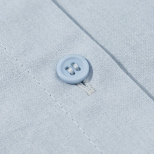 Macro shot of light blue fabric texture with matching four-hole button and fine stitching