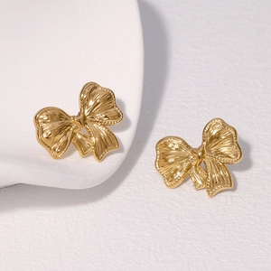 Elegant gold bow earrings in minimalist stainless steel displayed on a white tray