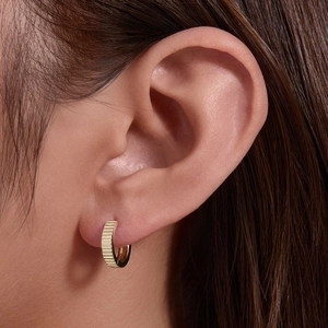 Elegant gold-tone striped hoop earrings with a minimalist geometric texture on female model