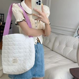 Close-up of heart-shaped quilted pattern and purple shoulder strap on large tote bag