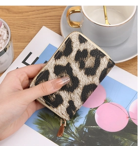 Close-up of leopard print faux leather zipper wallet held over a coffee table scene