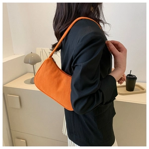 Detail of orange corduroy crescent shoulder bag shown on model in a modern setting