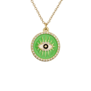 Gold evil eye necklace with green enamel and clear cubic zirconia on white background