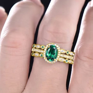 Macro close-up of a luxury three-piece ring set with oval green gem and gold finish