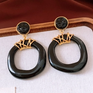 Detail of vintage resin hoop earrings featuring black and gold irregular pendant