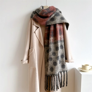 Detailed view of soft cashmere-feel scarf with gray red dot pattern and long fringe trim