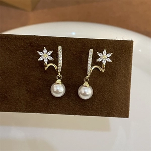 Detail view of gold flower earrings with pink zircons and white pearl drops