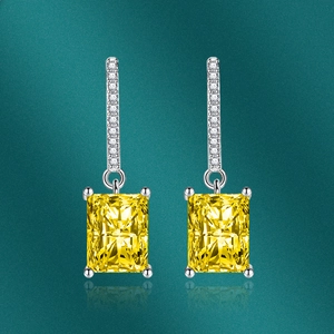 Macro shot of silver drop earrings with emerald-cut yellow gemstones and pavé accents