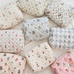 Vue à plat de trousses de maquillage en coton matelassé avec motifs d'ours et de fleurs