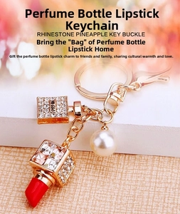 Detail of crystal perfume bottle and red lipstick pendants on a gold car keychain