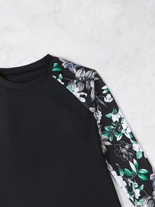 Flat lay of a long sleeve sun protection swimsuit with floral sleeves on marble background