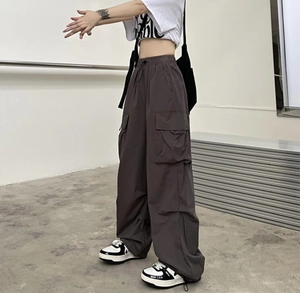 Detail view of dark grey wide-leg cargo pants with multiple pockets and drawstring waist