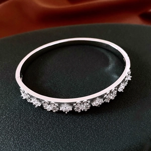 Détail d'un bracelet articulé argenté avec motifs floraux en cristal sur surface noire