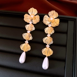 Dettaglio di orecchini dorati con fiori di zircone e nappe di perle eleganti