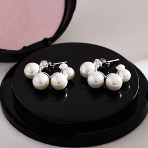 Close-up of five white pearls arranged in a curve on a silver-tone stud earring