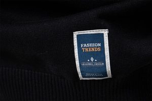 Détail de l'étiquette tissée bleue sur la texture d'un pull en maille noire de haute qualité