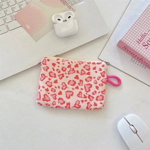 Flat lay of pink heart leopard print coin purse with wrist strap and laptop background