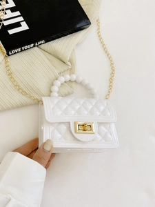 White quilted PVC jelly bag with pearl handle and gold chain strap shown on decorative books