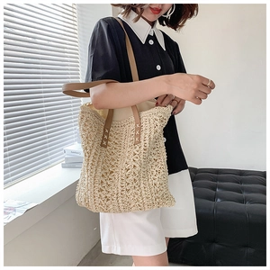 Close-up of hollow woven pattern and brown leather straps on a beige shoulder tote bag