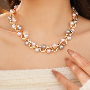 Gros plan d'un collier vintage avec perles blanches, roses, grises et détails en cristaux