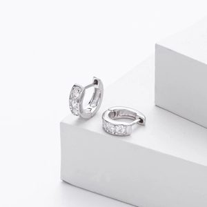 Detail view of silver S925 huggie earrings with sparkling inlaid cubic zirconia stones