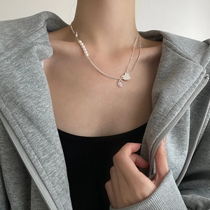 Detail of 925 sterling silver necklace with asymmetric pearls and heart charm on model