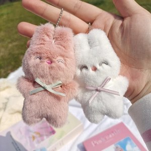 Détail de porte-clés lapin en peluche rose et blanc montrant la texture douce et broderie
