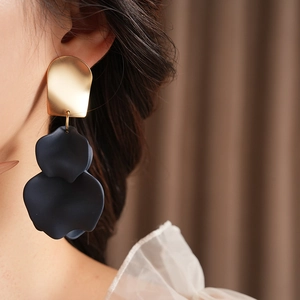 Close-up of model wearing gold and black irregular flower petals drop earrings