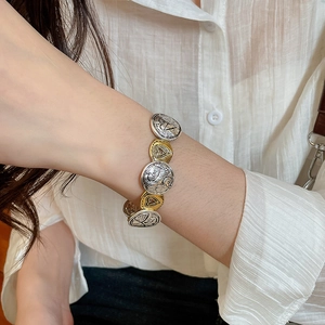 Close-up of two-tone heart chain bracelet with Love engraving on a woman's wrist