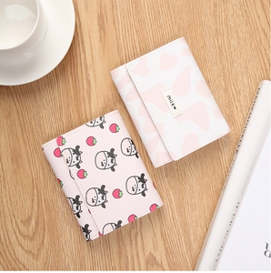 Detailed view of trifold wallet with cow and strawberry prints on light wood background