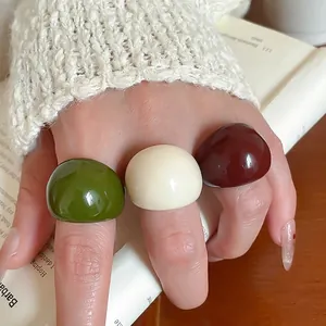 Three minimalist resin rings in olive green, cream white, and reddish brown finishes