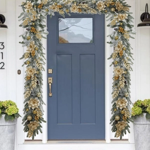 Close-up of frosted Christmas wreath with golden flowers and berries on a blue door