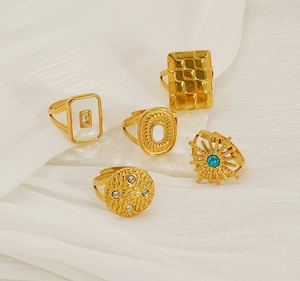 Set of five vintage gold-plated geometric adjustable rings on white silk fabric