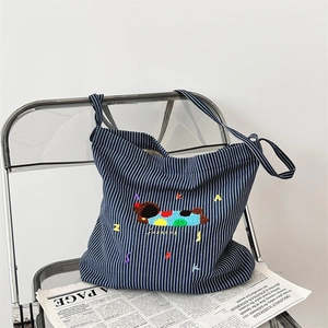 Close-up of cute dog embroidery on navy blue striped canvas tote bag with textured finish