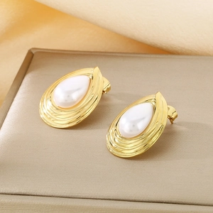 Detail view of gold teardrop pearl earrings on a beige velvet jewelry box stand