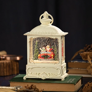 Vintage Christmas snow globe lantern with Santa in red car on rustic books