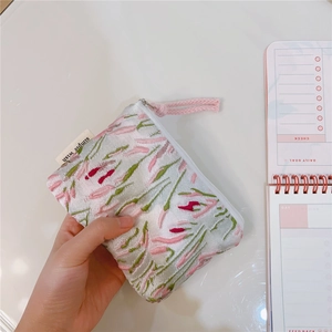 Detailed shot of pink floral jacquard coin purse held in hand with simple wish tag