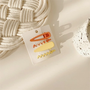 Set of 4 matte orange and yellow hair clips on card, including teardrop and wave shapes