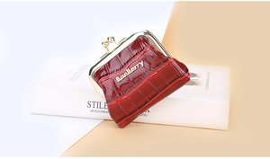 Macro shot of red glossy crocodile textured coin purse with golden metal clasp closure