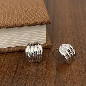 Detail view of silver polished croissant style stud earrings on a wood background