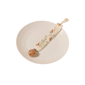 Attache-tétine en coton fleuri avec clip en bois sur une assiette en céramique