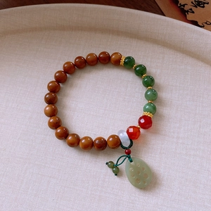 Detail of jade lotus pendant on a Chinese style wooden beaded bracelet with agate beads
