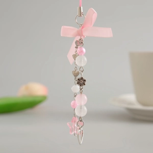 Detailed close-up of a pink beaded phone strap with ribbon bows and heart charms