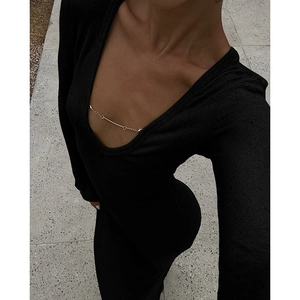 Détail du décolleté en U avec chaîne dorée sur une robe moulante en maille noire