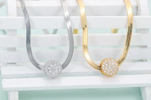 Close-up of gold and silver snake bone necklaces with sparkling round rhinestone pendants