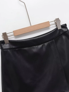 Detalle de la cintura de falda corta de cuero PU negro en una percha de madera natural
