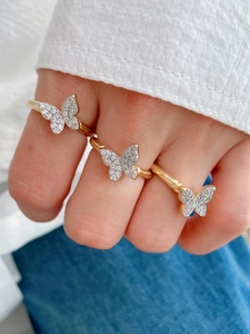 Close-up of elegant gold butterfly rings with micro-paved rhinestones on a hand