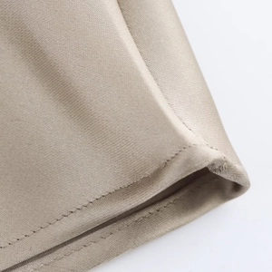 Vue macro de l'ourlet en satin champagne avec des coutures de finition précises