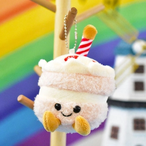 Close-up of a cute plush cake pendant keychain with a smiley face and soft texture.